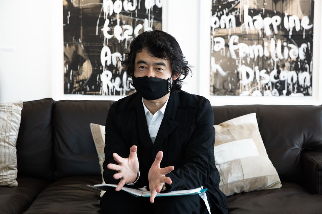 取材時に着用したのは「ブラック コム デ ギャルソン(BLACK COMME des GARÇONS)」。渋谷パルコで店長を務めた際に出店を誘致するなど思い入れのあるブランドだという。マスクは「ダイアナ(DIANA)」からプレゼントされたもの。 Image by FASHIONSNAP
