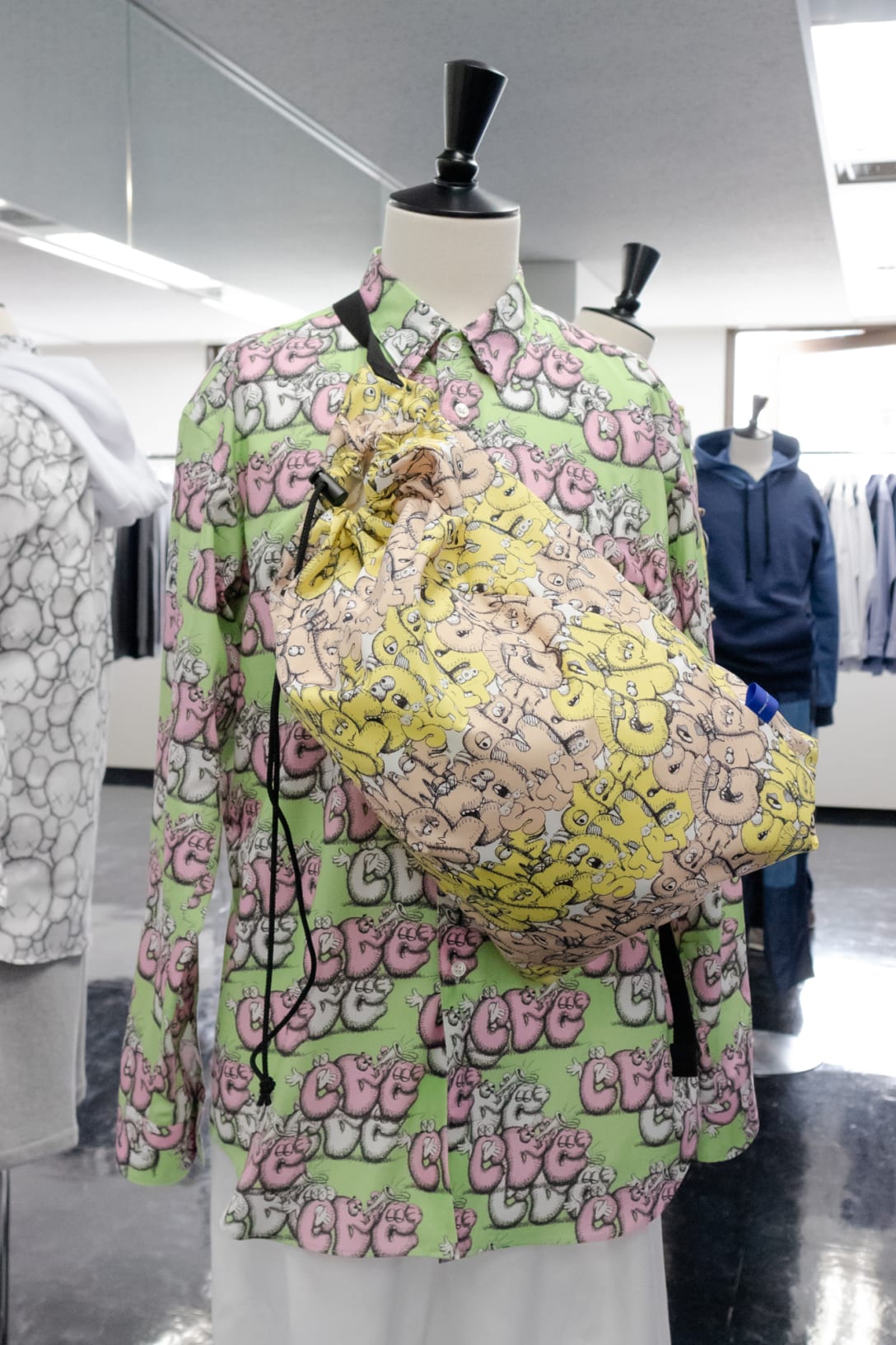 カウズによる「CDG」のグラフィックをあしらったシャツとバッグ Image by FASHIOSNNAP.COM
